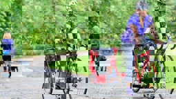 Woman cycling on cycle path pulling small child in trailer