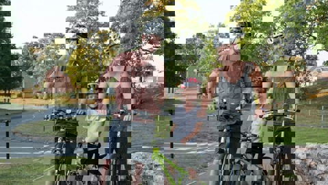 Mum and dad with daughter in a park, wearing helmets and standing with their bikes smiling