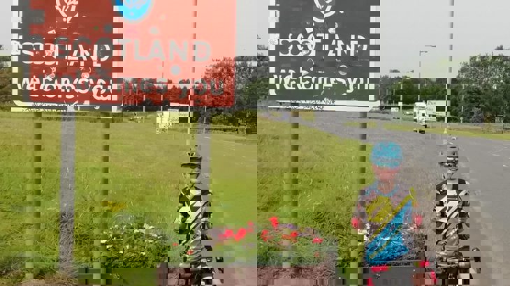 boy on bike next to Scotland sign
