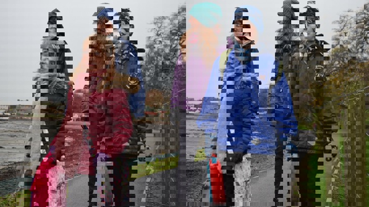 Two women and two children walk to school. They are wrapped up warm.