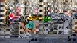 Two friends with bicycles stop at the end of a road next to a sign which reads "Road open to" followed by symbols for a parent and child, push scooter, wheelchair and bicycle.