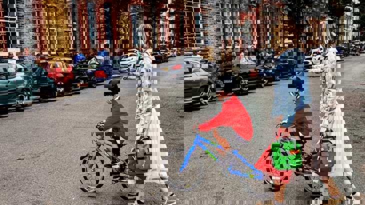 Child in school uniform on bike on road outside school