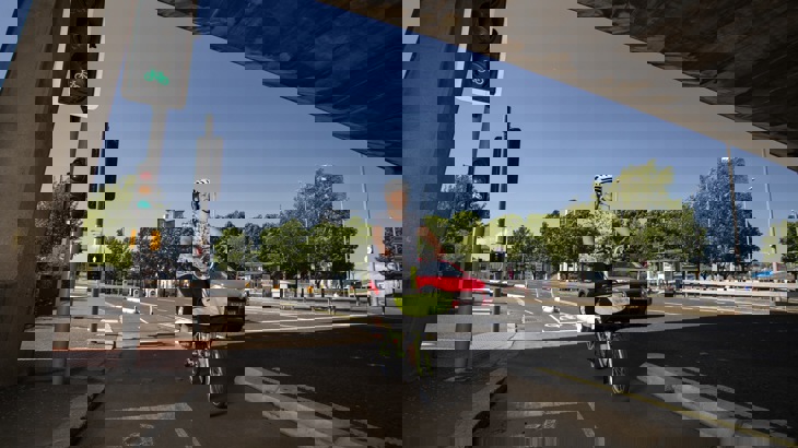 Case study Claire Griffin cycling her folding bike on new segregated cyclepath in Belfast - Middlepath Street, Belfast with red car passing in background