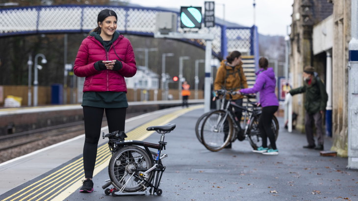 Woman at the station next to her folding ebike commuter