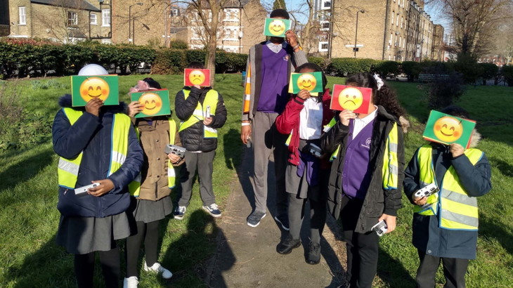 group of children outside with emoji pictures in front of their faces