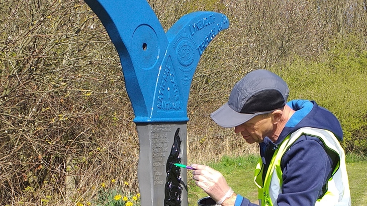 Volunteer painting milepost on National Route 1