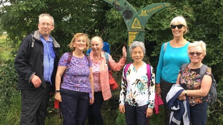 Group of men and women pictured at a mile post on Walk Wheel Cycle Trust National Cycle Network -Route 92. The walking group are exploring the route along the Foyle river