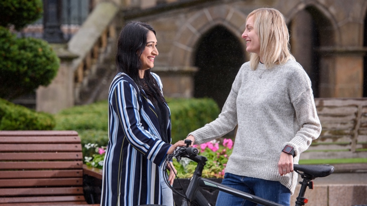 Two women share advice stood beside a bicycle