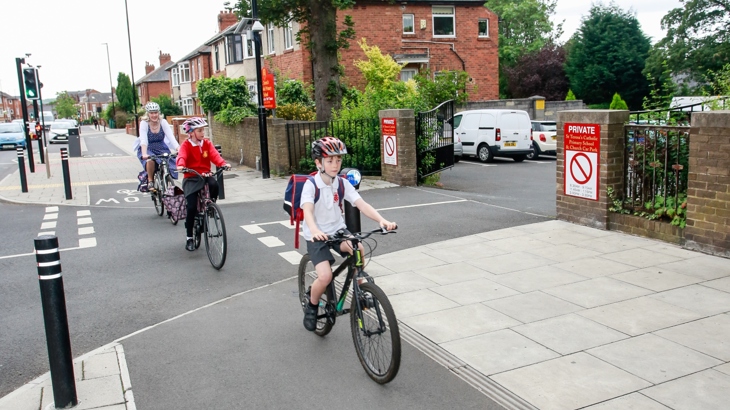 Family cycling to school over new infrastructure junction