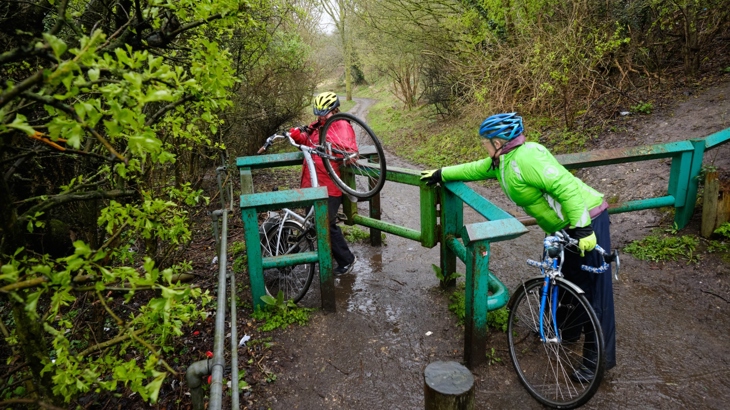 People on bikes struggling with a barrier gate in Reading on National Route 4