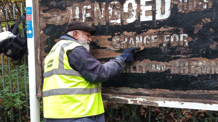 Volunteer cleaning and repainting sign on National Cycle Network 