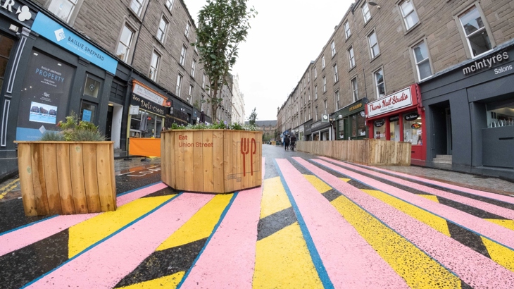 Union Street, Dundee with large wooden planters in the road and colourful geometric street art on the ground.