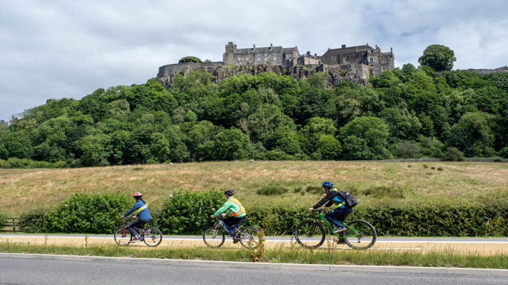 Young people cycling on segregated infrastructure on Dumbarton Road with Stirling Castle in the background. 