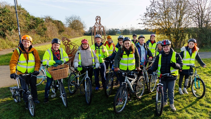 A group of people poses in a park with their bicycles