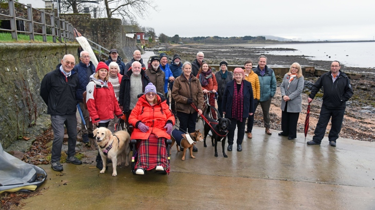 Members of the community come together to celebrate the opening of the Fairlie Coastal Path. They pose for a photo which shows the new route in the background, running along the waterfront.