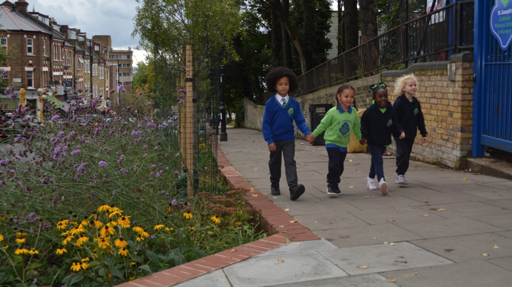 a group of children walk on the pavement outside their school
