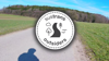 'Walk Wheel Cycle Trust Outsiders' logo with little simple drawings of a winding path surrounded by trees and birds. A dotted line like a plotted route encircles it.