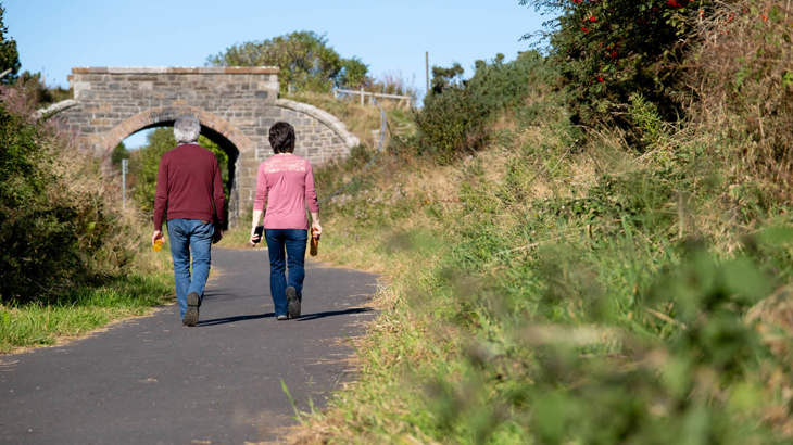 Two adults walk along newly improved Cullen to Portknockie path on the National Cycle Network.