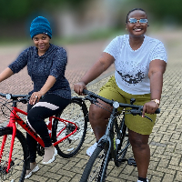 Two women stood smiling with their cycles side by side 