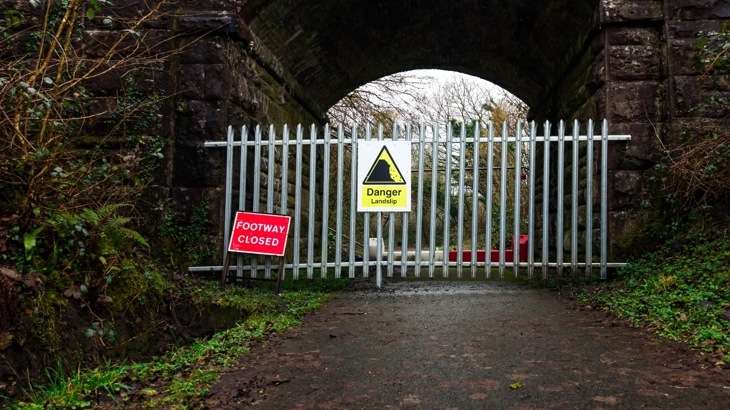 A large fence blocking off a part of National Cycle Network Route 47. In front of the fence is a sign that reads "Footway closed"